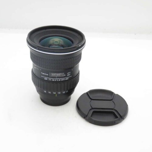 Camera lens with lens cap on a white surface.