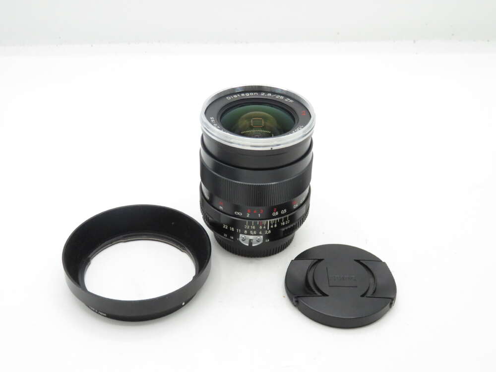 IMG_0565 Camera lens with a lens hood and lens cap on a white background.