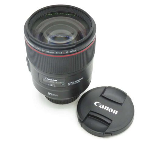 Canon 85mm f/1.4 lens with cap placed beside it.