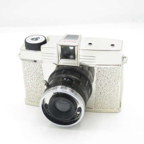 Vintage silver camera with a textured grip, black lens, and a film advance dial on top.