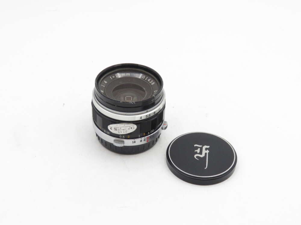 IMG_0638 A 21mm f/4 camera lens with a detached lens cap on a white background.