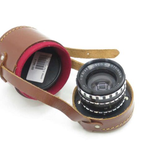 Vintage camera lens with "ISCO GOTTINGEN" engraving, placed inside a brown leather case with red interior lining.