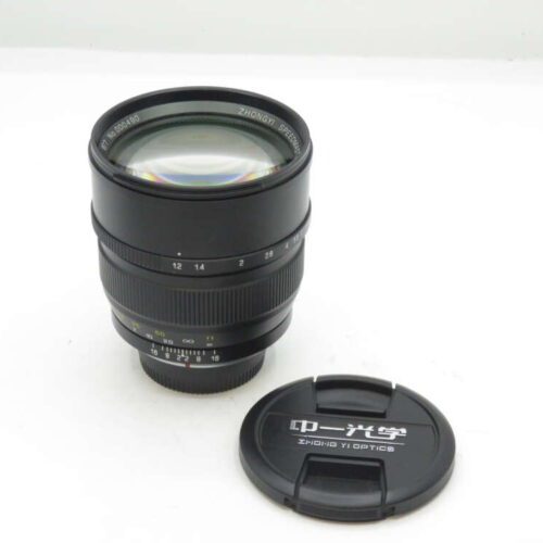 A black Zhong Yi Optics camera lens with a detached lens cap on a white background.