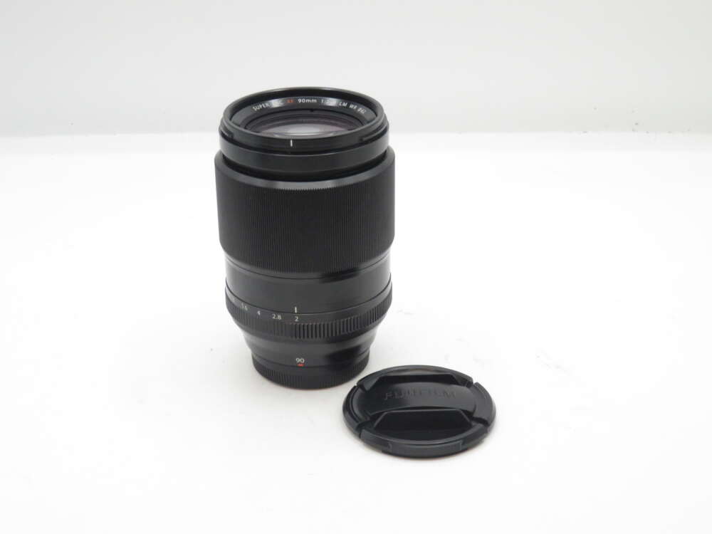 IMG_0844 Black camera lens with a lens cap on a white surface.