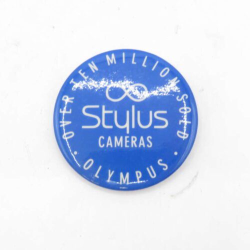 Blue round badge with the text "Over Ten Million Sold" at the top, "Stylus Cameras" in the center, and "Olympus" at the bottom.
