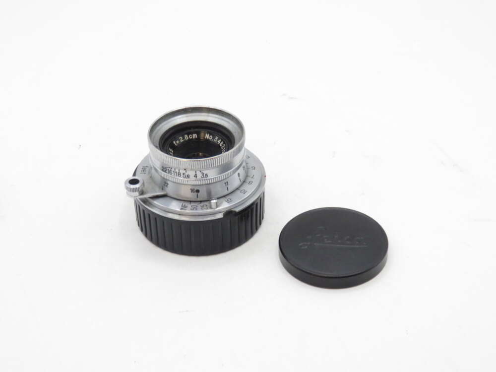 IMG_1189 Vintage camera lens with engraved markings and an adjacent black lens cap.