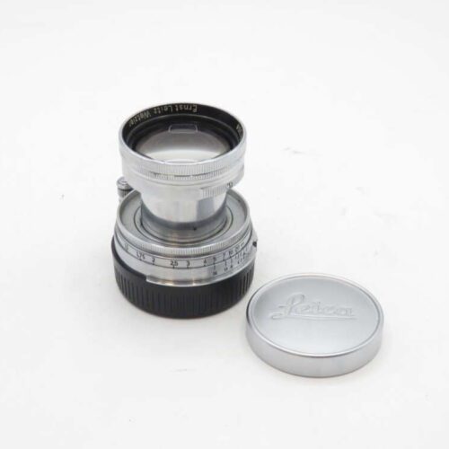 Leica camera lens with a detached lens cap placed beside it.