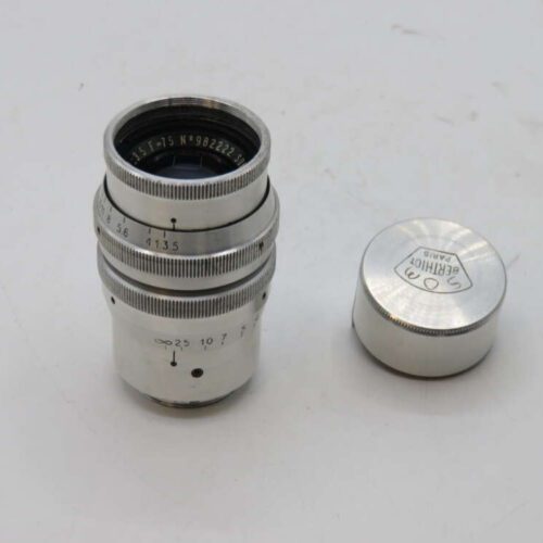 Silver camera lens with detached lens cap on white background.