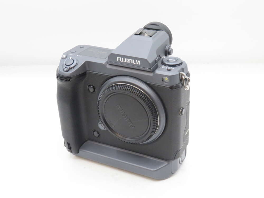 IMG_1785 Fujifilm camera body with a lens mount cap, featuring grip and control dials.