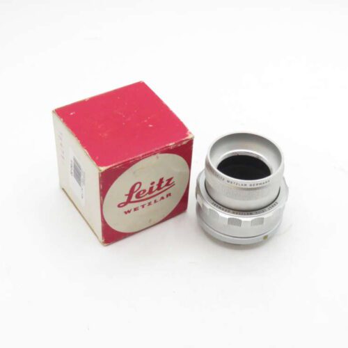 Leitz Wetzlar silver camera lens beside its red and white box.