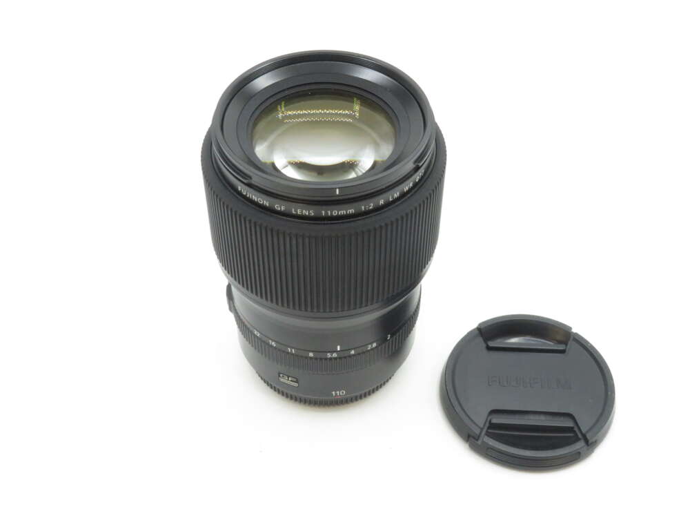 IMG_1870 Black Fujifilm GF Lens 110mm f/2 R LM WR with a lens cap placed beside it.