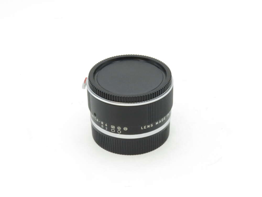IMG_1874 Black camera lens with a silver ring, lens cap on, and text "Lens Made" partially visible.