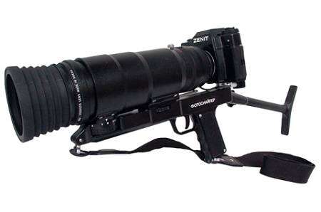 A camera with a large telephoto lens mounted on a rifle-like support system.