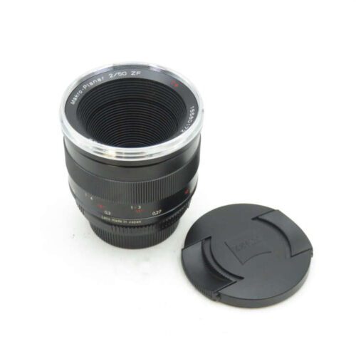 Camera lens with 'Makro-Planar 2/50 ZE' on it, alongside the lens cap, against a white background.