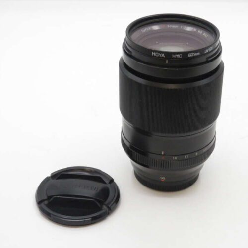 Camera lens with its detached lens cap on a white background.