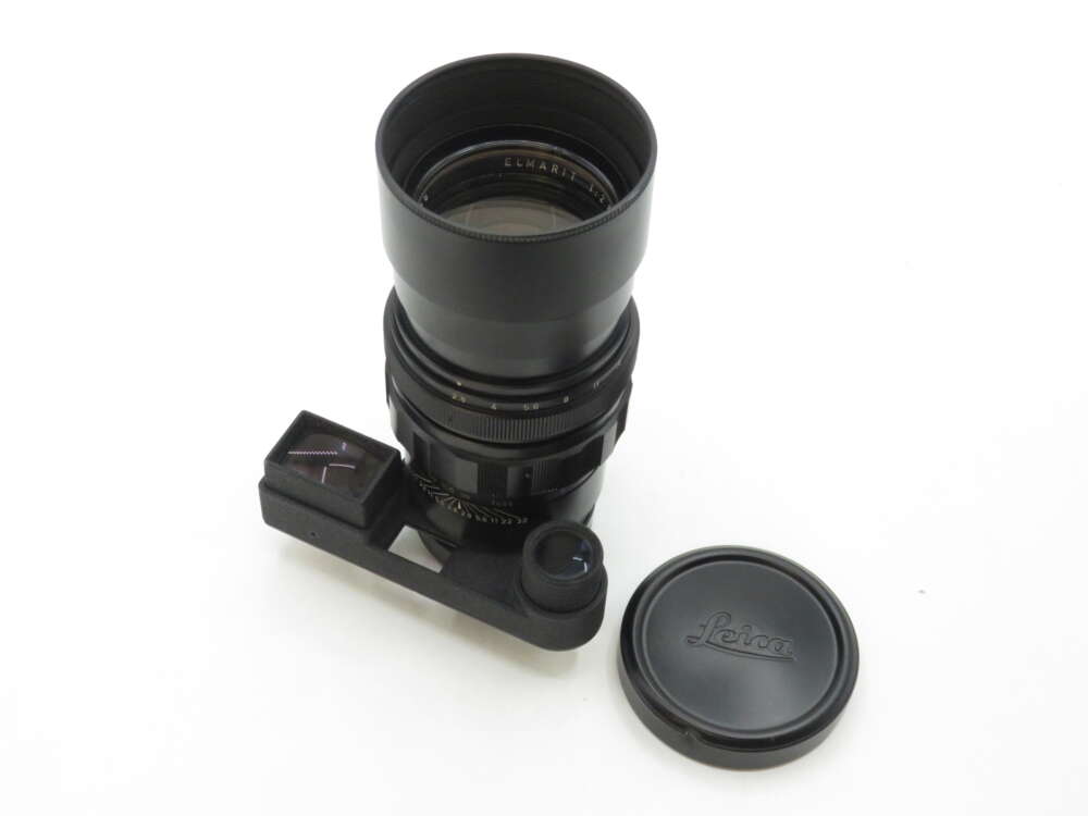 IMG_2406 Telephoto camera lens with lens cover and attached rangefinder, with Leica logo on the cover, placed on a white background.