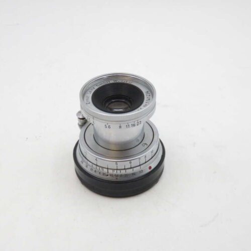 Silver camera lens with focus and aperture adjustment rings on a white background.