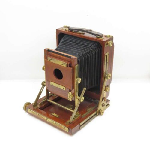 Vintage wooden bellows camera with brass fittings on a white background.
