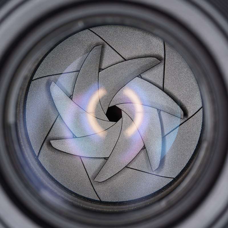 Close-up of a camera lens aperture with overlapping blades.