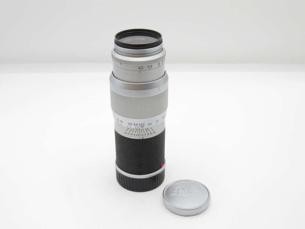 IMG_2940 Silver Leica camera lens with black grip, next to a detached silver lens cap.