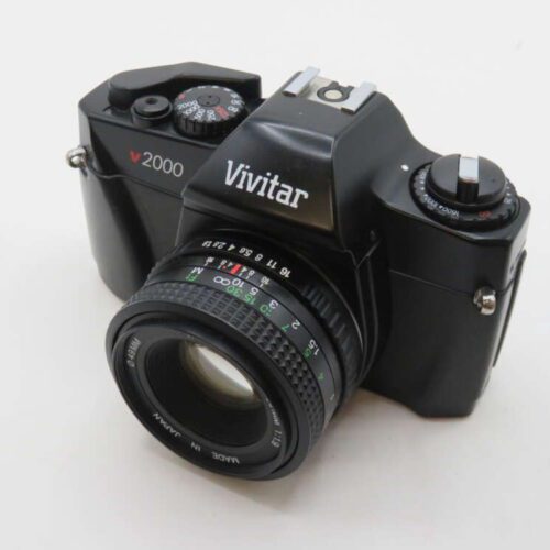 A black Vivitar V2000 film camera with a lens attached, featuring dials and buttons on the top for adjusting settings.