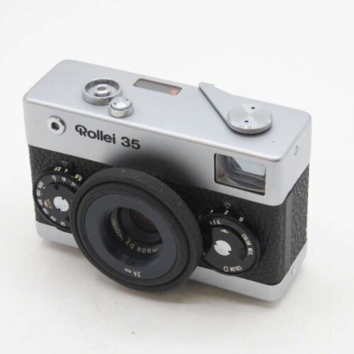 A Rollei 35 camera with a silver and black design, featuring a protruding lens and adjustment dials on the front.