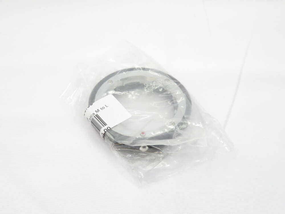 IMG_0490 A camera lens adapter ring in a plastic bag with a barcode and label showing 'Leica M to L' on a white background.