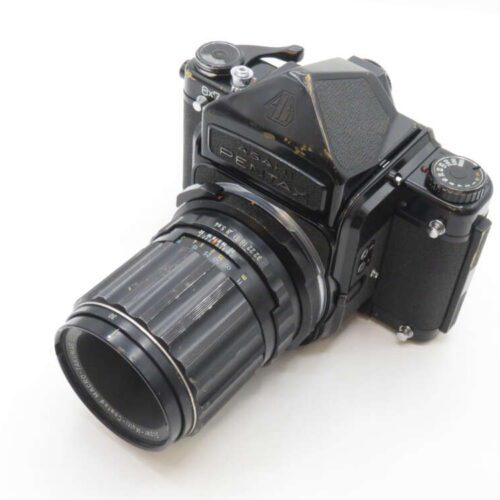A vintage black Pentax 6x7 medium format film camera with a large, dark grey lens attached, placed on a white background.