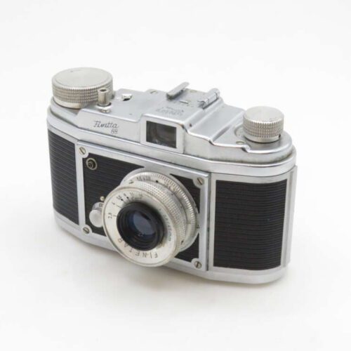 A vintage Finetta 88 film camera with a metal body and black textured grips, featuring a prominent lens and various dials on the top plate, set against a plain white background.