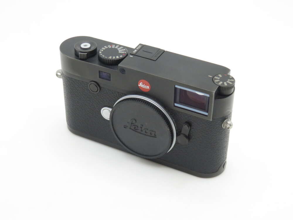 IMG_0793 A black Leica camera with a lens cap, featuring a red Leica logo on the front and manual dials on top, set against a plain white background.