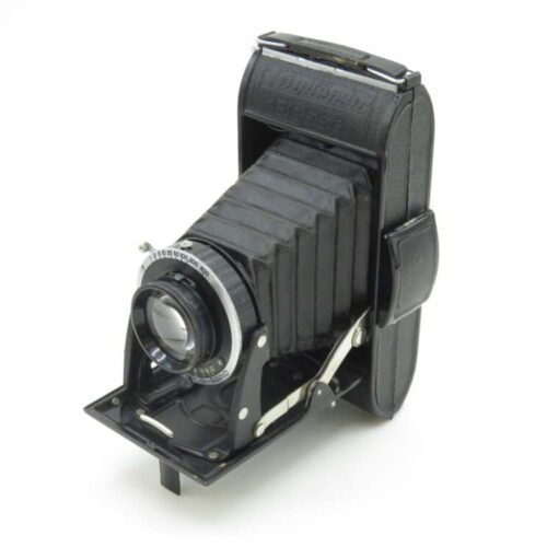 A vintage folding bellows camera with a black body and silver lens mechanism, standing open on a white background.