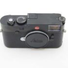 A black Leica rangefinder camera with a classic design, featuring manual dials on the top, and the Leica logo above the lens mount.