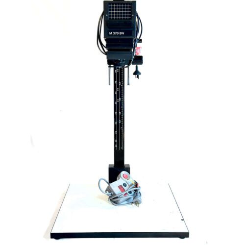 An M 370 BW photo enlarger with a vertical stand and a control box with cables placed at the base.