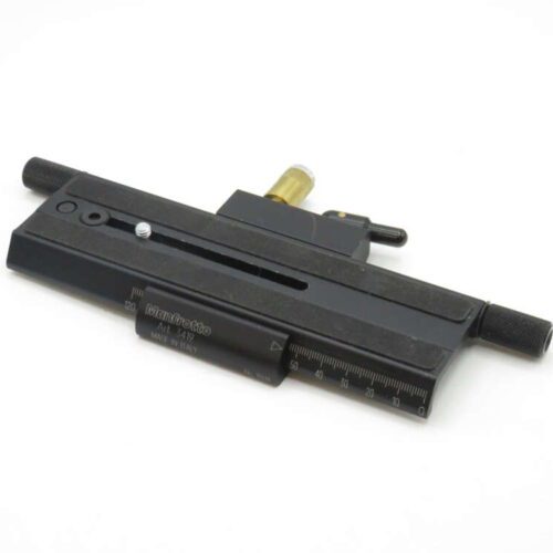 A black Manfrotto sliding plate with a ruler marking, used for precise camera positioning, featuring dials for adjustments.