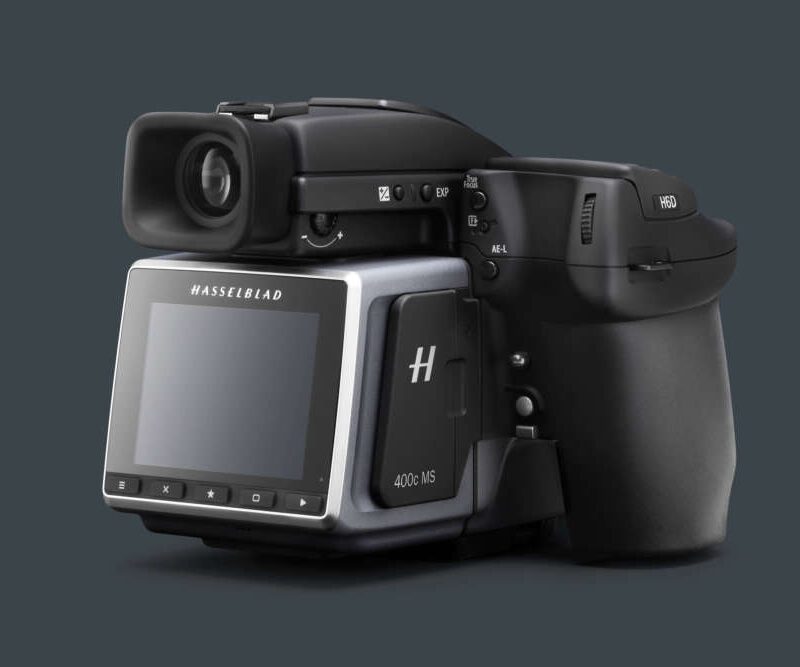 A Hasselblad H6D-400c medium format camera, featuring a digital back and ergonomic design, set against a dark background.