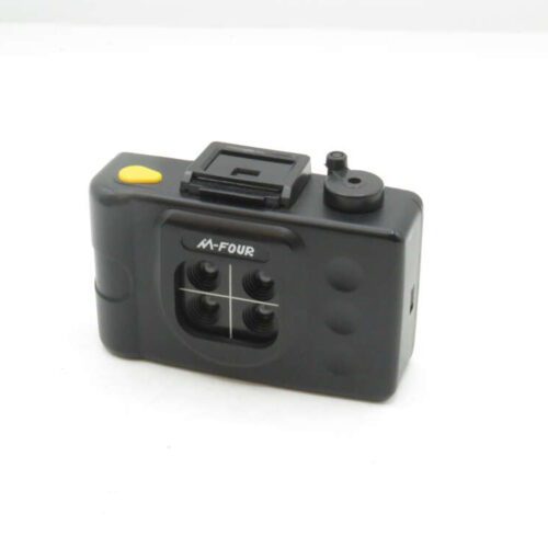 A small black multi-lens camera with four lenses arranged in a square pattern, featuring a yellow shutter button on the top and the label 'M-Four' on the front.