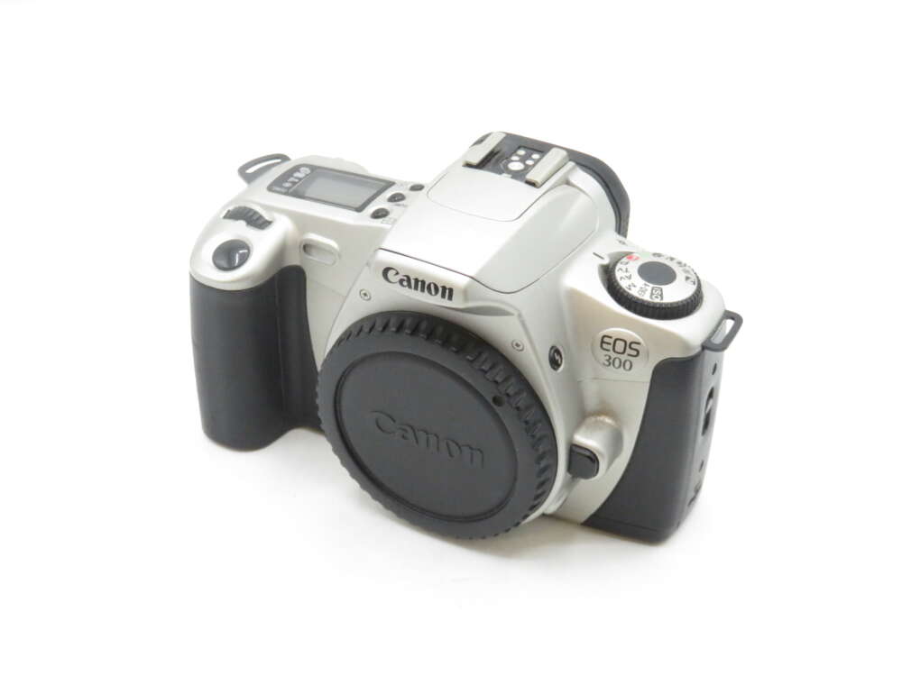 IMG_1483 Canon EOS 300 film camera with a silver body and a black grip, featuring a lens cap on, mode dial, and LCD screen on top.