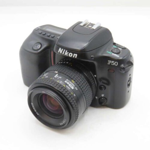 A Nikon F50 film camera with an AF Nikkor lens attached, positioned on a white surface.