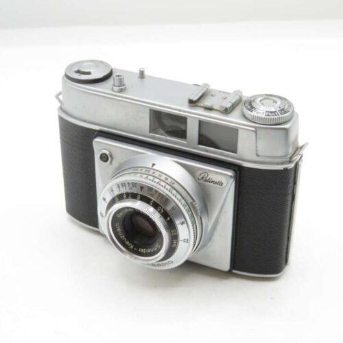 A vintage Retinette camera with a black textured body and silver metal details, featuring a prominent lens with engraved settings and a viewfinder on top, positioned on a plain white background.