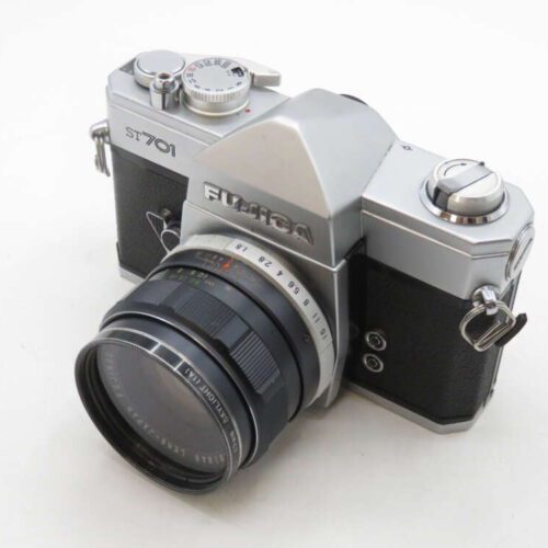 A vintage Fujica ST701 film camera with a metallic body and black detailing, featuring a large lens with focus and aperture rings, and a top-mounted shutter speed dial.