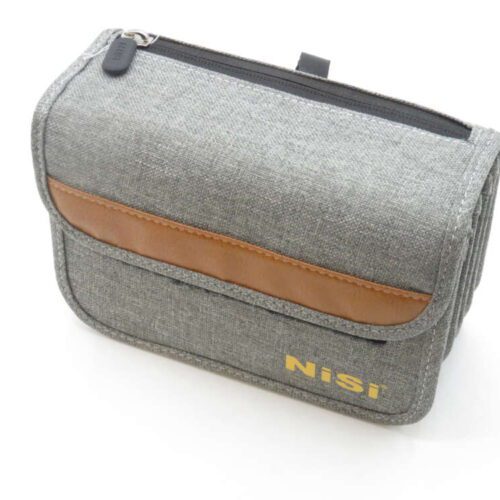 A grey fabric pouch with a brown leather accent and a zipper on top, featuring the brand name 'Nisi' in yellow letters on the front.