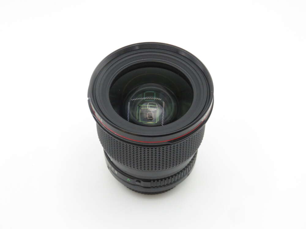 A camera lens with a wide aperture viewed from above, featuring a prominent glass element and a textured focus ring, set against a plain white background.