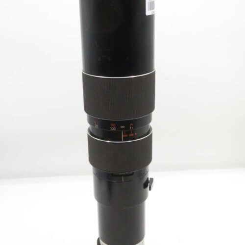 A black telephoto camera lens with adjustable focus rings and distance markings displayed in a well-lit environment.