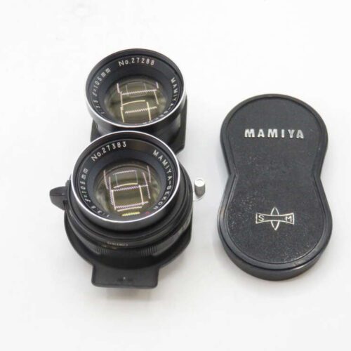 A pair of Mamiya camera lenses with a matching lens cap on a white background. The lenses are labeled as 105mm f/3.5, and the lens cap is black, marked with the Mamiya logo.