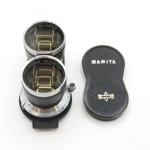 A Mamiya twin-lens reflex camera lens attachment with a black protective cover next to it. The lenses are labelled with their specifications and brand details.