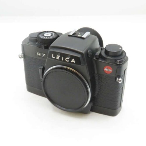 A Leica R7 film camera with a black body and lens cap attached, featuring textured grip panels and signature Leica branding on the front.