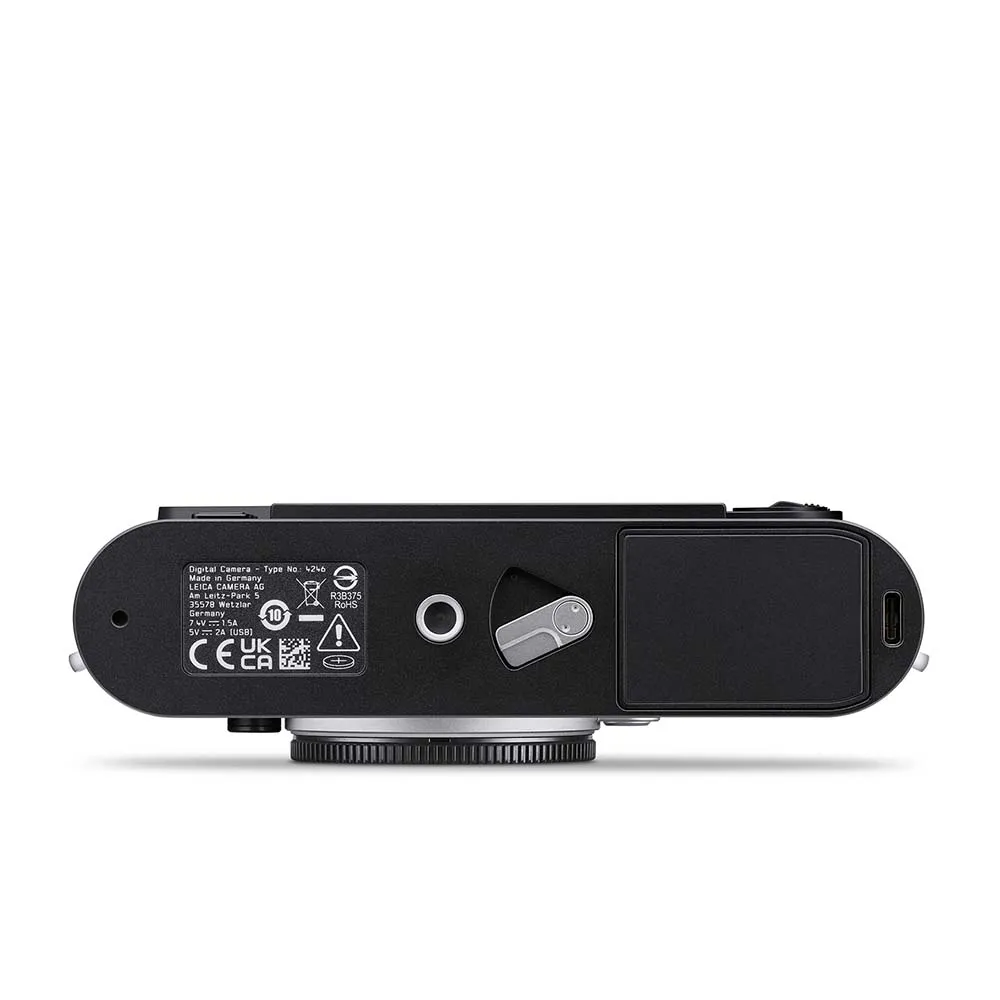 Bottom view of a black digital camera showing certification labels, a tripod mount, battery compartment, and a USB-C port.