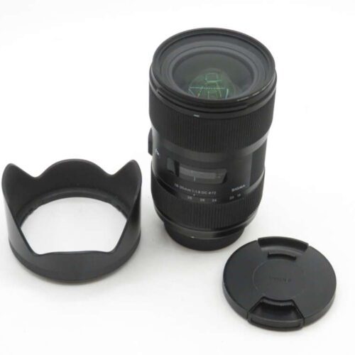 A camera lens with a detached lens hood and lens cap on a white background.