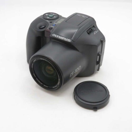 An Olympus IS-100 film camera with a separate lens cap placed next to it on a white background.