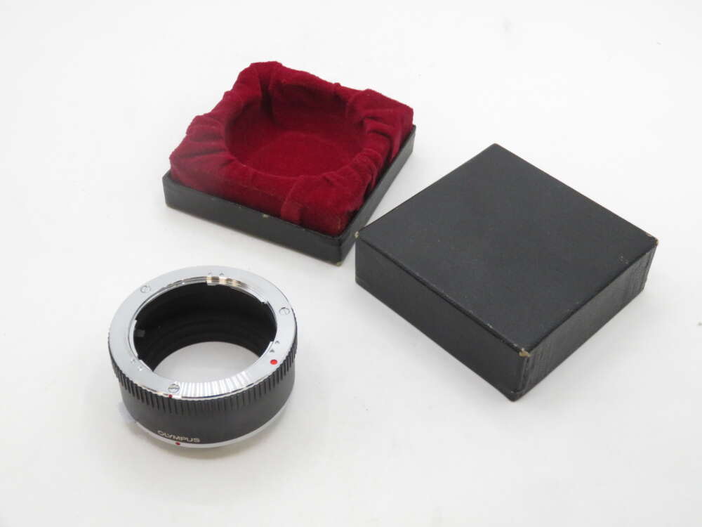 IMG_2132 A camera lens adapter ring placed next to its black box with a red velvet interior lining.
